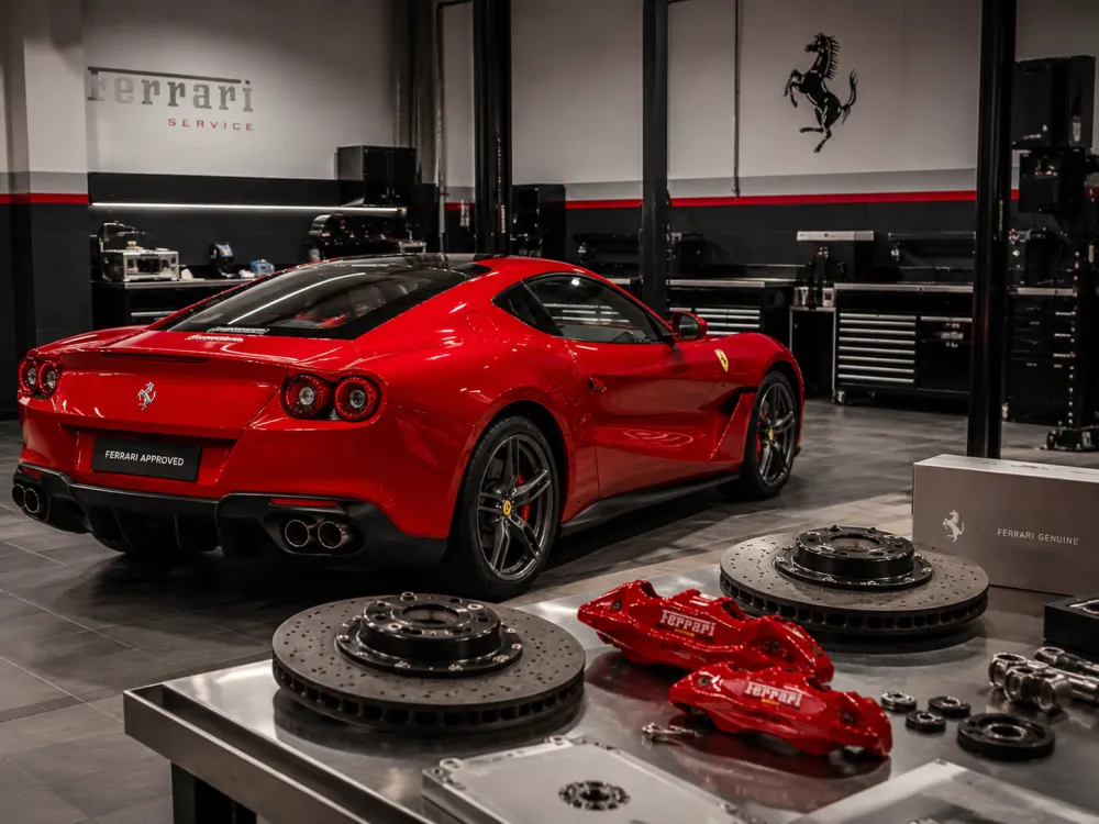 A red Ferrari in a clean workshop with genuine ferrari parts arranged neatly 