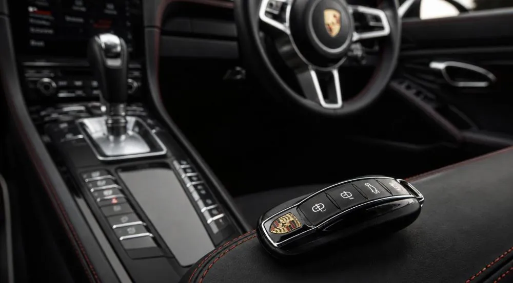 Luxury car key placed beside a premium sports car interior